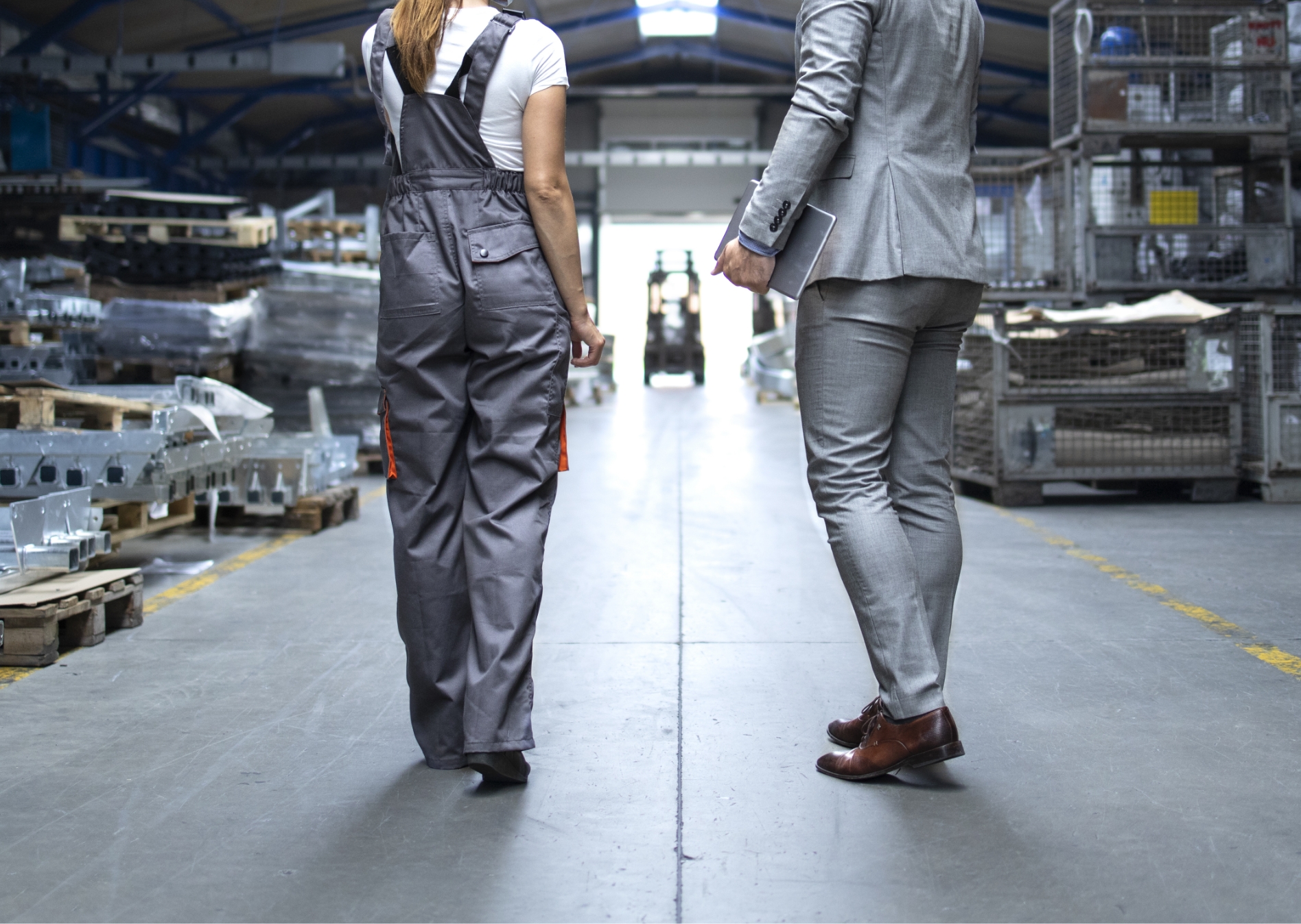 Zwei Personen die in einer Lagerhalle laufen und sich unterhalten, von hinten aufgenommen