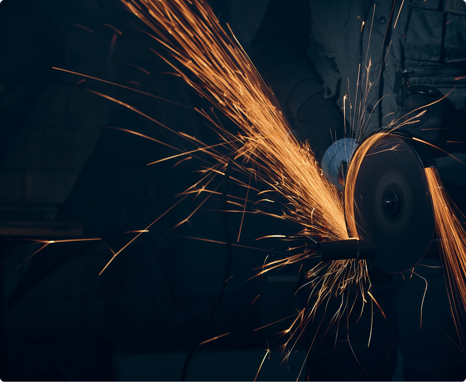 Orangener Funkenflug an einer Kreissäge in einem dunklen Raum