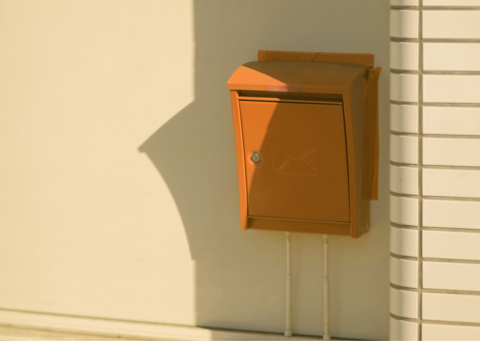 Gelber Briefkasten auf einer hellen Hauswand